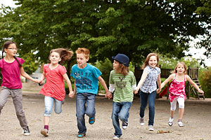 Sechs Kinder, freudig Hand-in-Hand laufend 